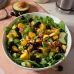Ensalada de mango, pepino, arándano y aguacate en un plato fresco y colorido
