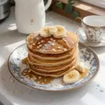Pancakes de plátano y avena servidos en un plato con frutas frescas