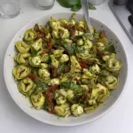 Plato de tortellini con pesto y verduras frescas