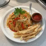 Plato de arroz con pollo servido con verduras frescas y especias aromáticas.